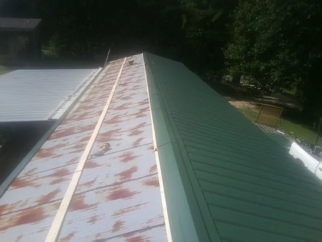 Old rusted panels beside newly installed green metal roofing — Wind Damage Roof Repair by Roofing Brothers in Mountain Rest