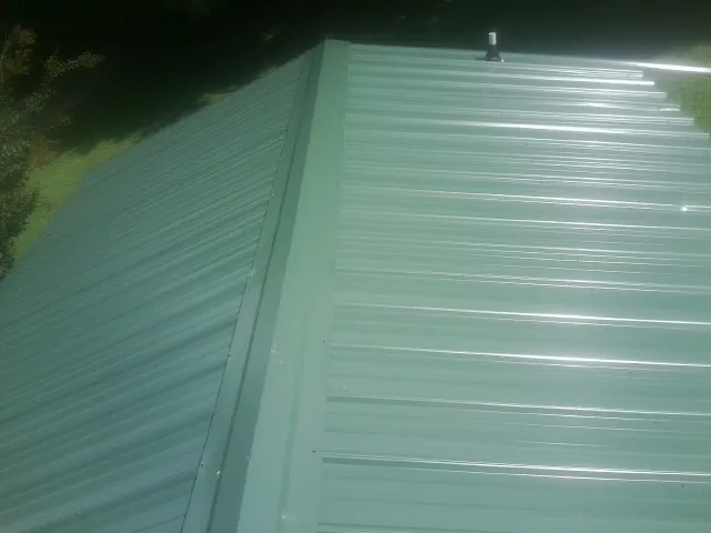 New green metal panels meeting at the ridge of a roof — Flat Roof Repair work by our crew in Mountain Rest