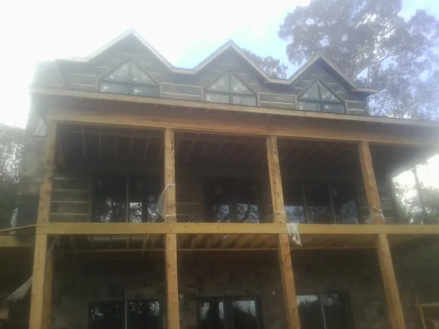 Dormers and porch framing on a large log home under construction — Roof Coating work by our crew in Mountain Rest