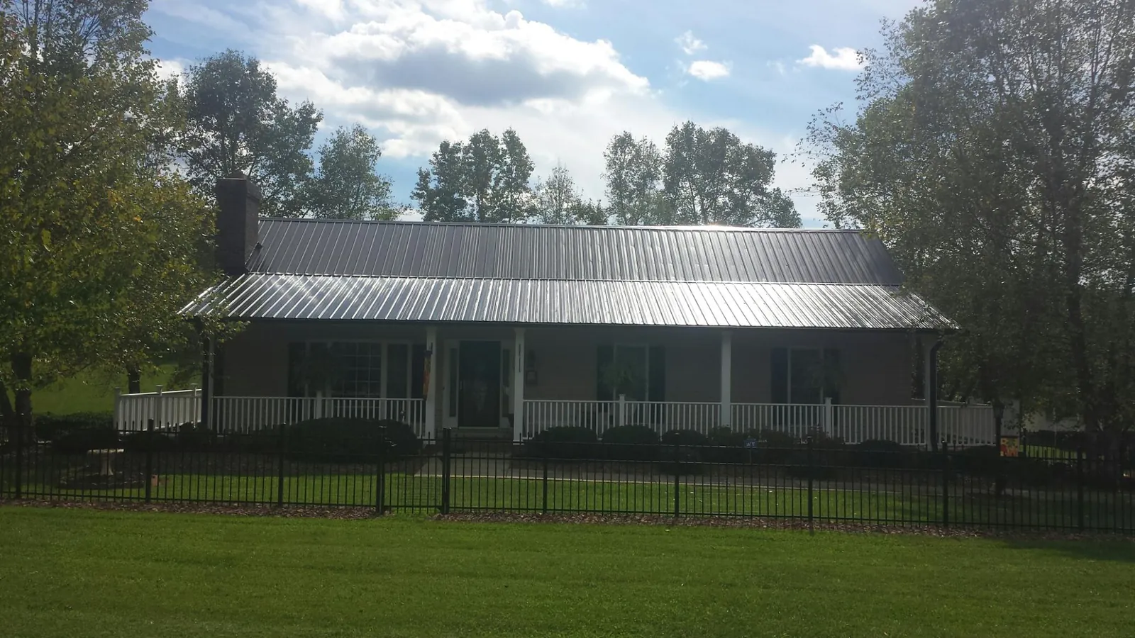 Gray metal roof on a brick ranch with a full width front porch — Gutter Guard Installation work by our crew in Mountain Rest