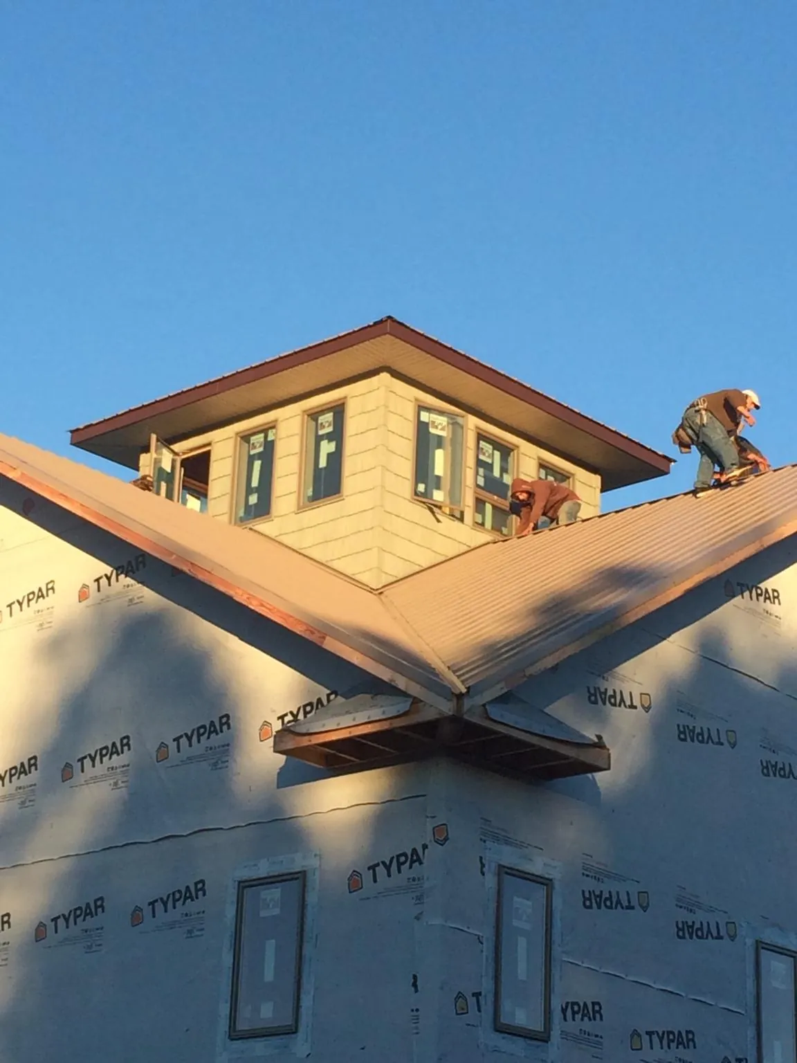 Roofers working around a rooftop cupola on a new metal roof at sunset — Roof Waterproofing in Mountain Rest by Roofing Brothers